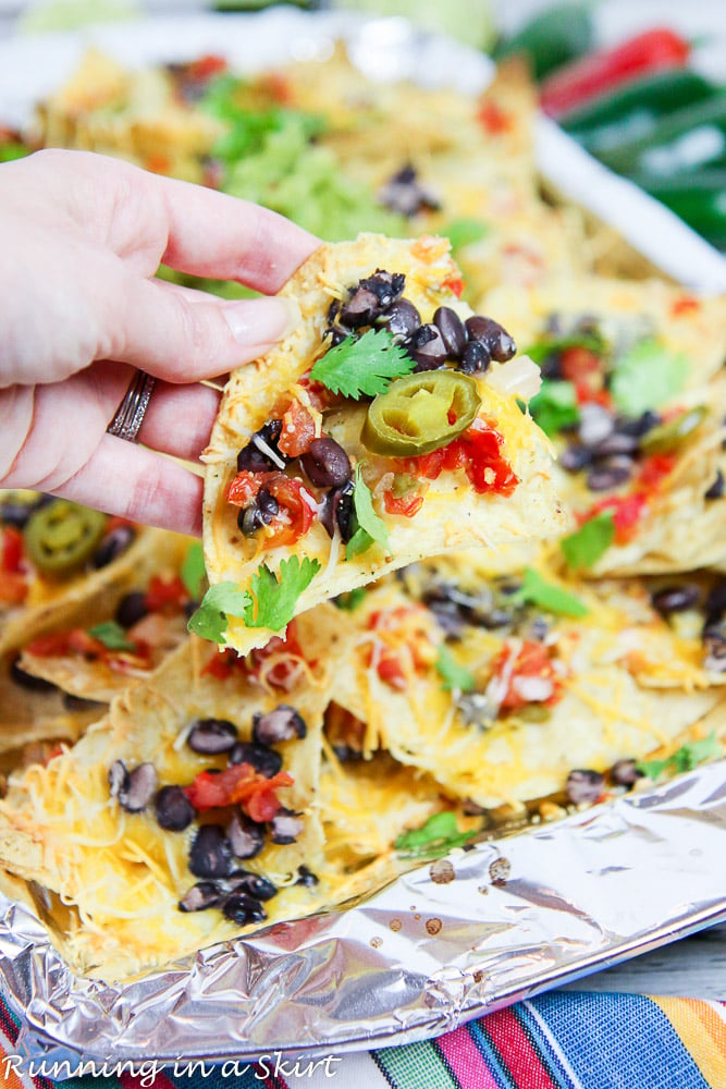 Hand holding chip of Sheet Pan Vegetarian Nachos - The Best Easy Nachos Recipe.