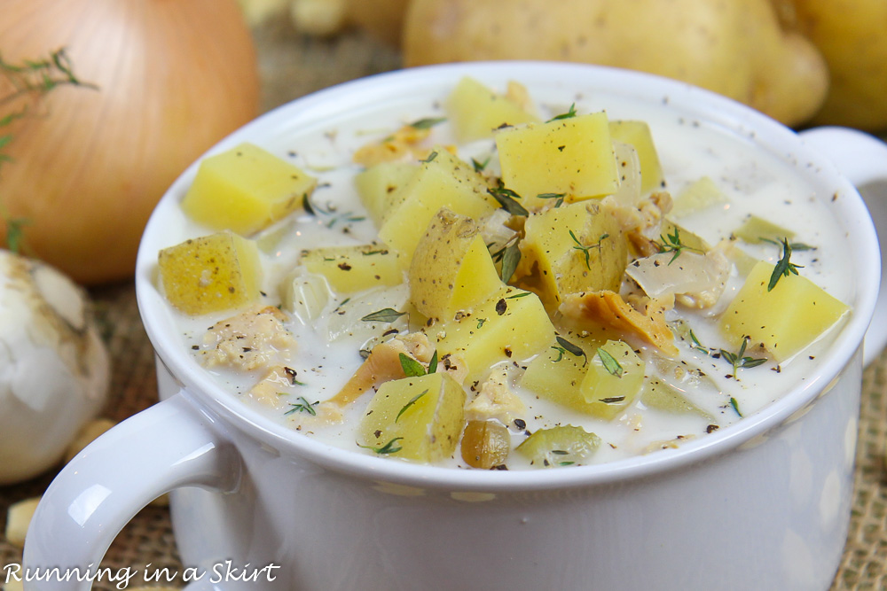 Crockpot Clam Chowder recipe in a white bowl with onions in the background.