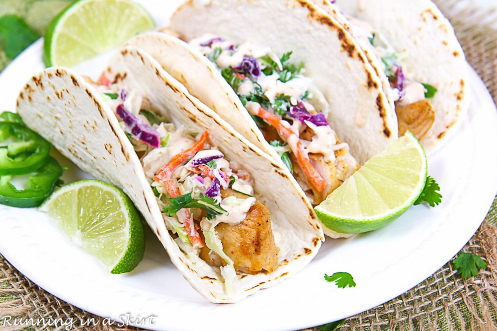 Close up of the fish tacos on a plate with a lime.