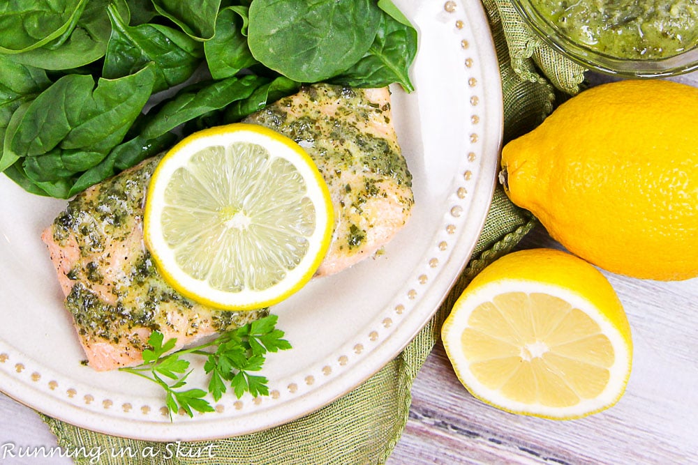 Salmon with a lemon slice and salad on a white plate.