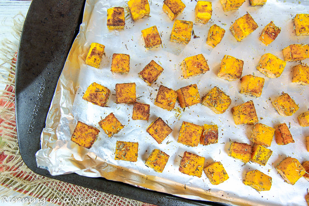 Cooked butternut squash on a baking sheet lined with foil.