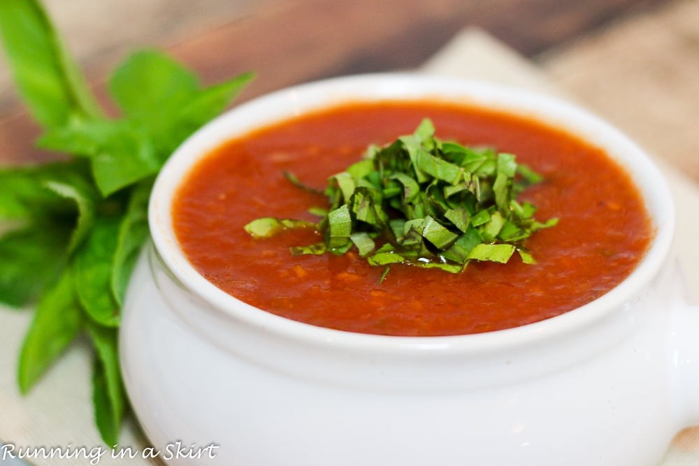 Easy Crock Pot Tomato Basil Soup in a white bowl with basil garnish on top.