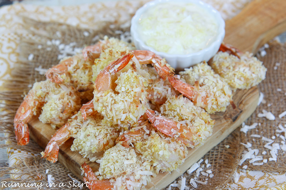 Oven Baked Coconut Shrimp piled on a wooden serving tray.