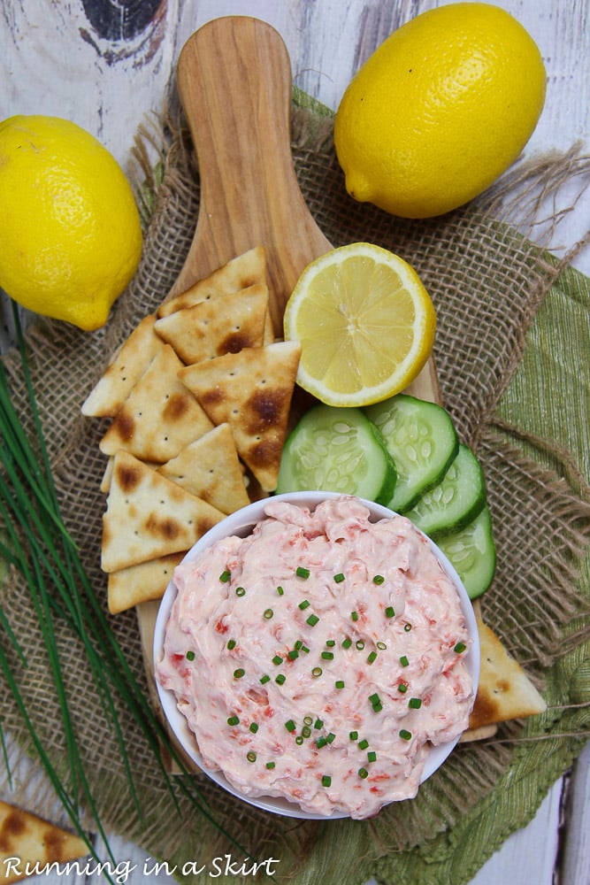 Overhead shot of Healthy Salmon Dip with crackers, cucumbers and lemon on a wood cutting board.