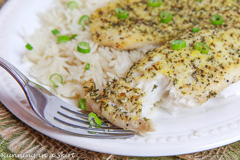 Baked Lemon Pepper Tilapia on a fork with a white plate and rice.