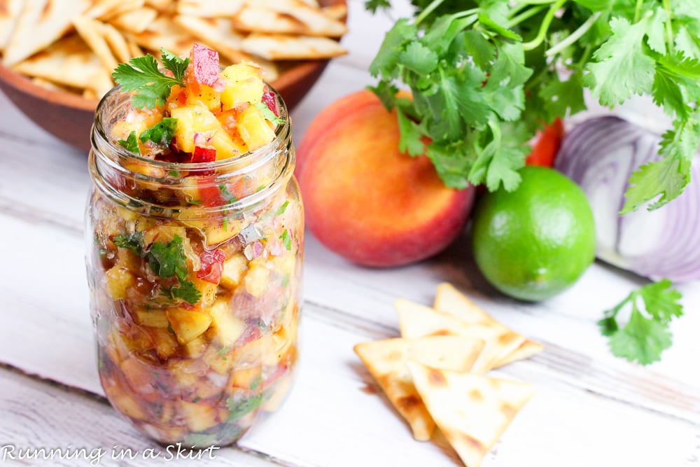 Fresh Peach Salsa recipe in a jar with peaches, lime, cilantro and chips in the background.