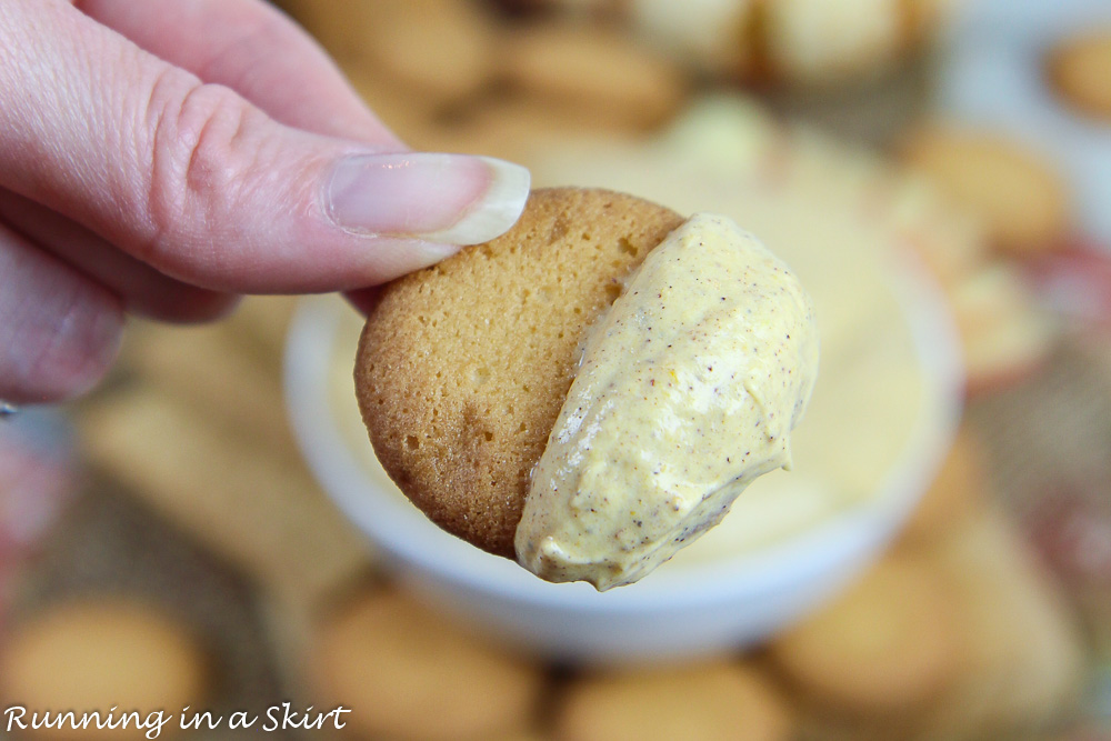 Hand holding cracker with Healthy Cheesecake Pumpkin Dip.