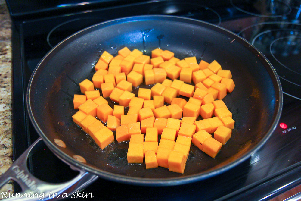 Butternut squash cooking in a pan on the stove top.