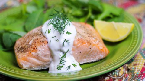 Baked Lemon Salmon with Creamy Dill Sauce on a green plate.