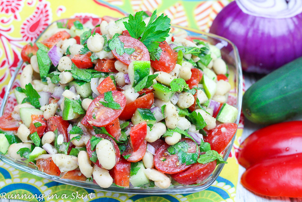 Vegan Bean Salad with fresh herbs, cucumber and tomato in a glass bowl.