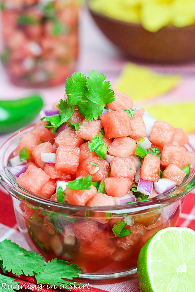Watermelon salsa is a glass bowl with chips in the background.