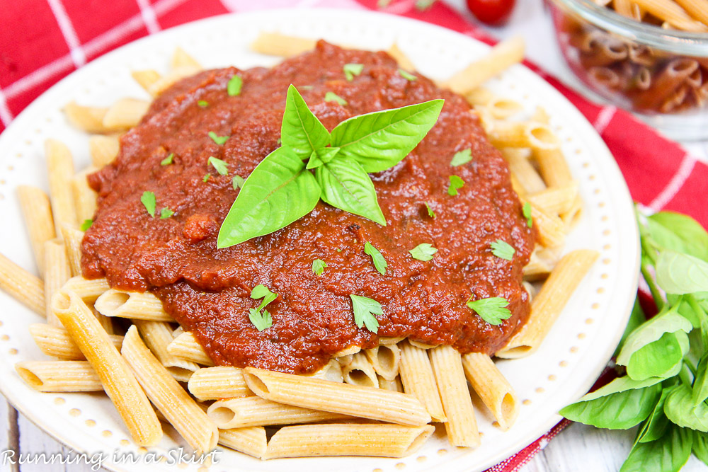 A vibrant red homemade marinara sauce in a slow cooker topped with fresh herbs.