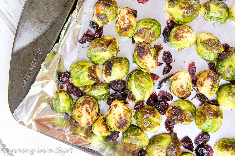 Process shot showing the sprouts and cranberries on a baking sheet.