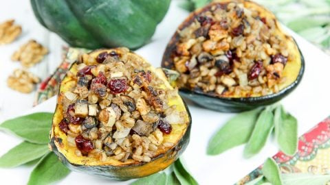 Stuffed acorn squash plated with fresh sage on a white plate.