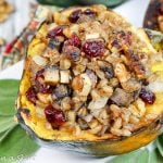 Stuffed acorn squash plated with fresh sage on a white plate.