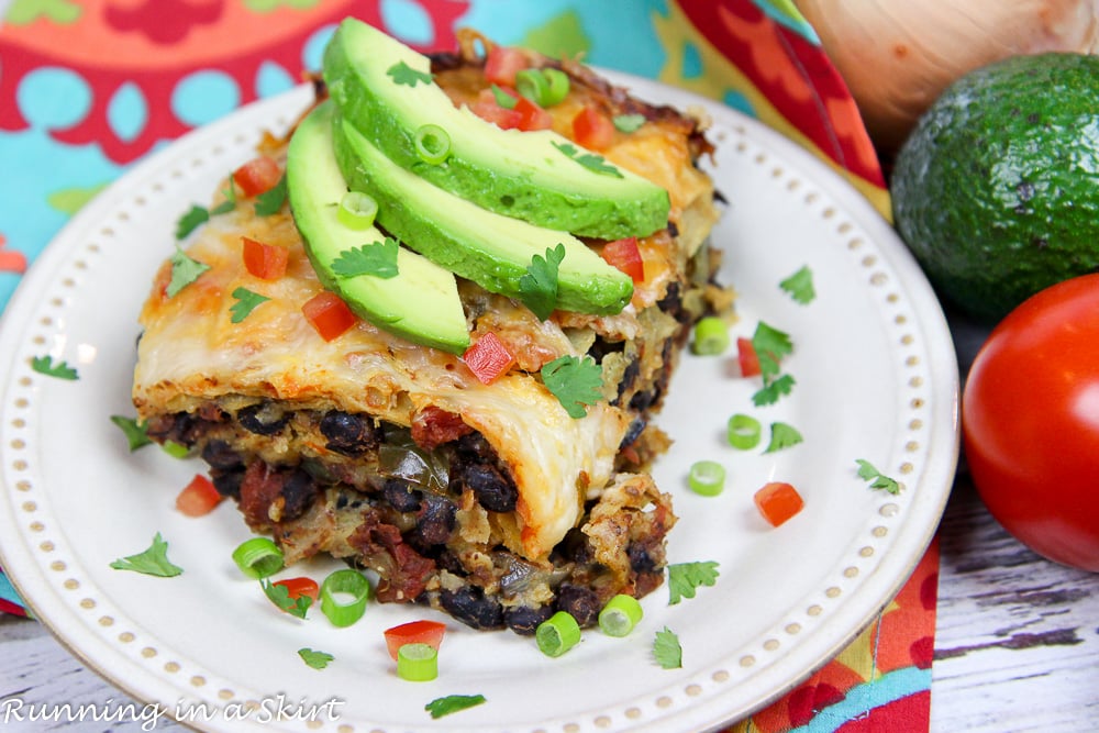 Crock Pot Vegetarian Enchilada Casserole on a white plate topped with garnishes.