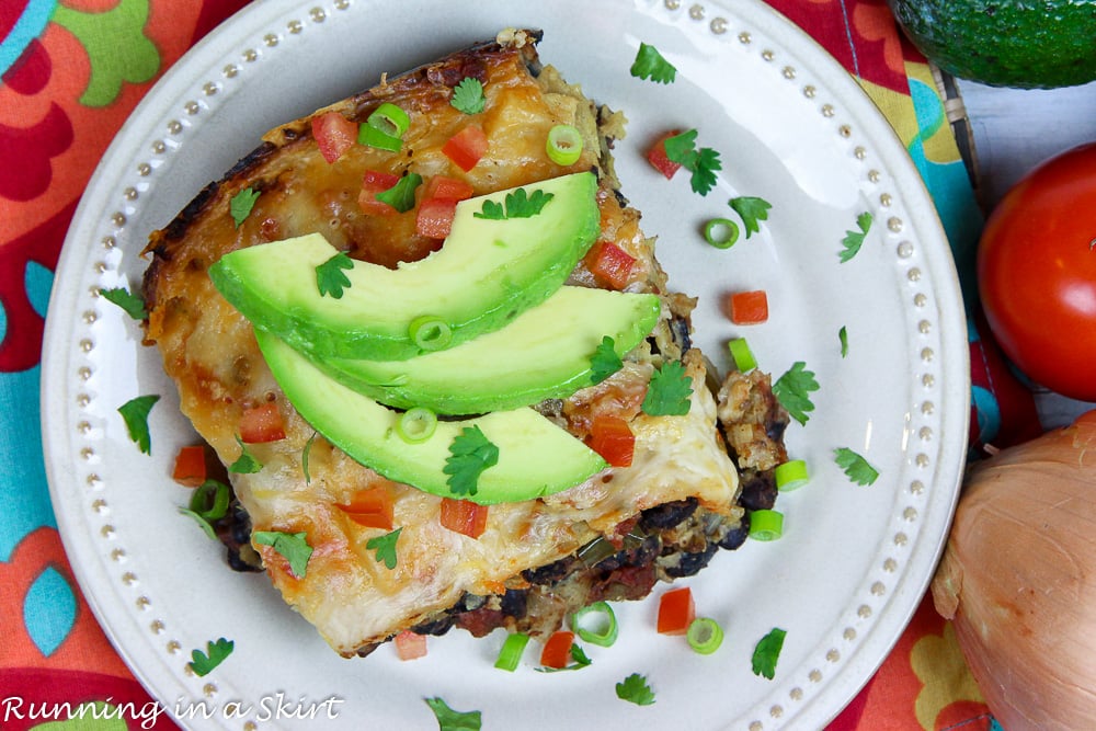 Crock Pot Vegetarian Enchilada Casserole on a white plate topped with garnishes.