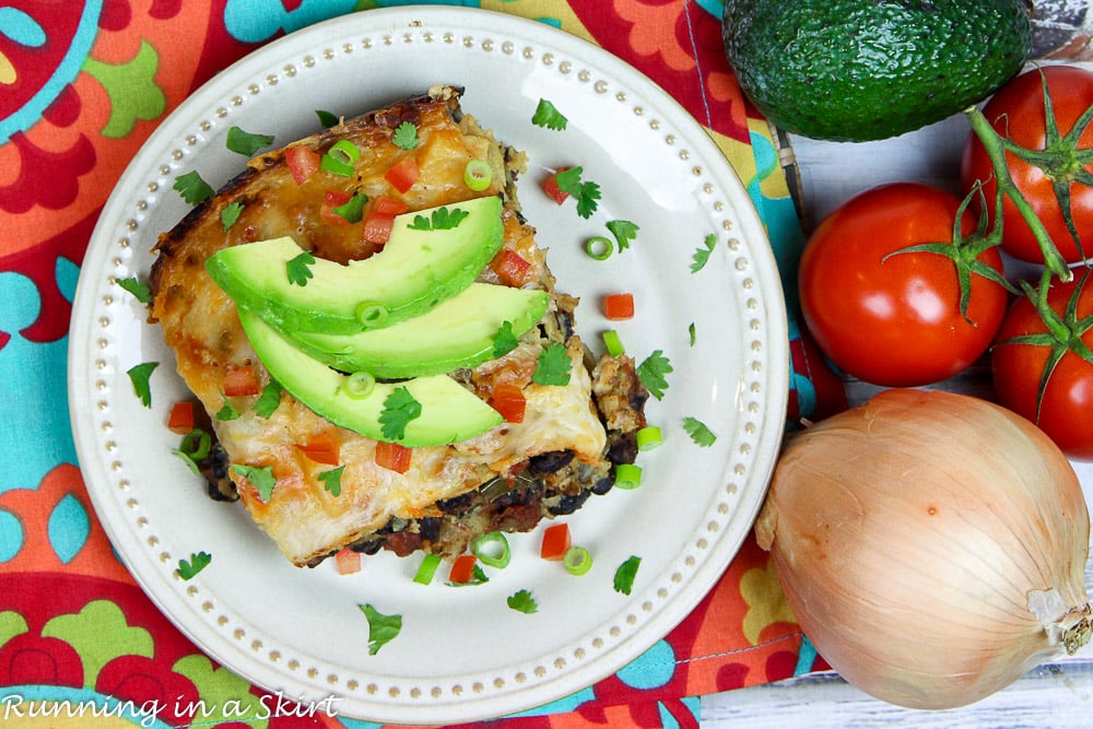 Crock Pot Vegetarian Enchilada Casserole on a white plate topped with garnishes.