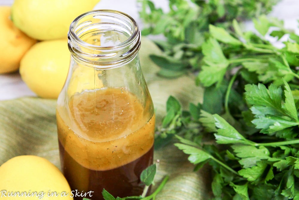 A bottle of red wine vinaigrette dressing with parsley and lemons.