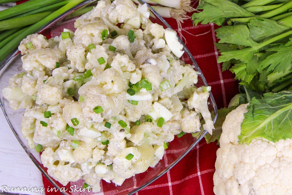 Overhead shot of Cauliflower Potato Salad topped with green onions on a red napkin.