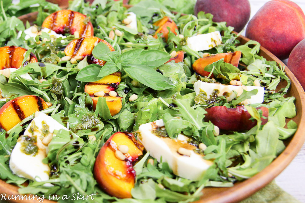 Caprese Grilled Peach Salad recipe on a plate with peaches in the background.