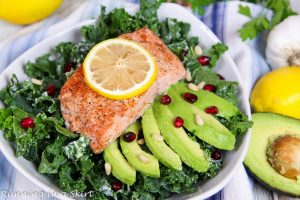 Baked Salmon Kale Salad with Tahini Dressing in a white bowl.