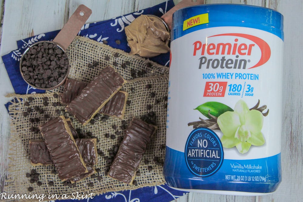 A pile of no bake peanut butter protein bars next to a container of protein powder.