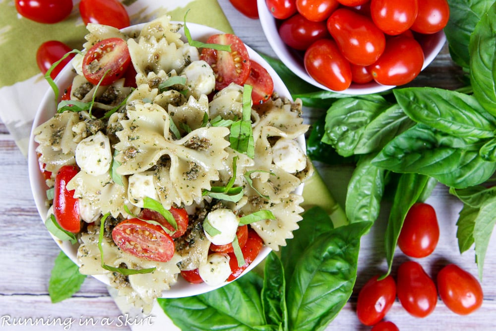 Caprese Pasta Salad with pesto - 4 Ingredient Pasta Salad in a white bowl overhead shot with fresh basil.