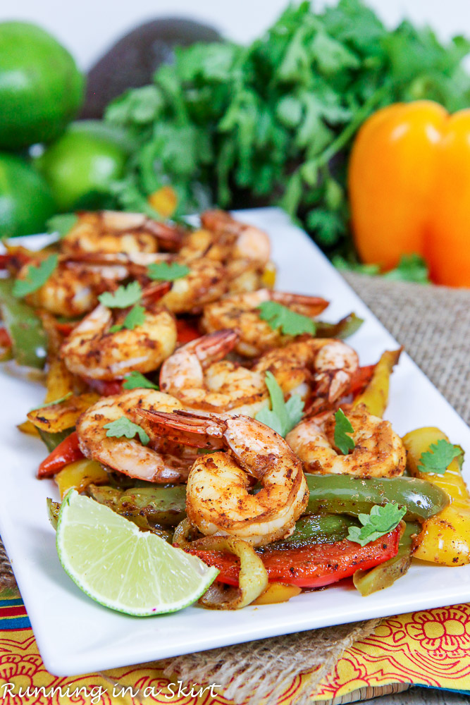 Sheet Pan Shrimp Fajitas on a white plate with a lime wedge.