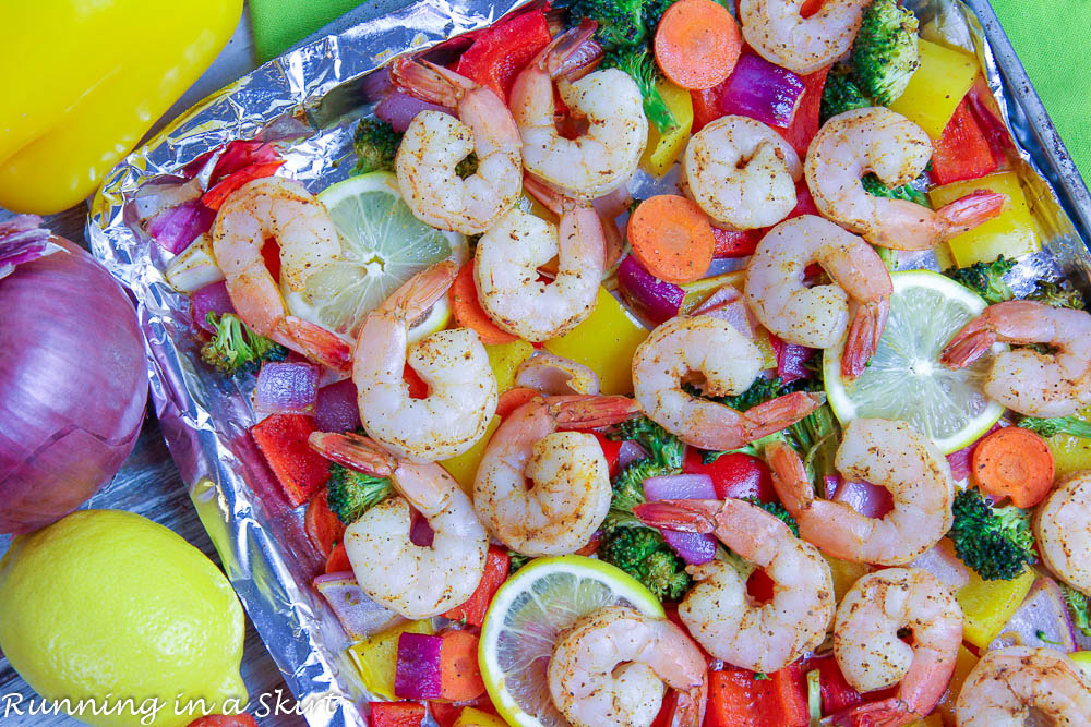 Shrimp, vegetables and lemons on a pan.