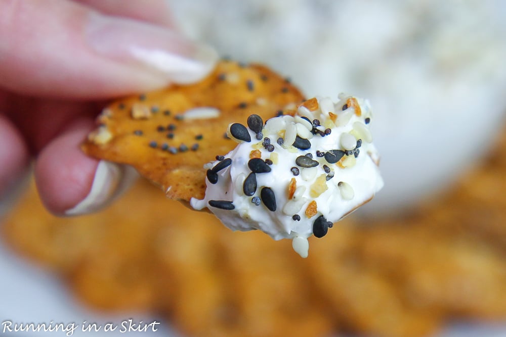 Dip on a pretzel held in a hand.