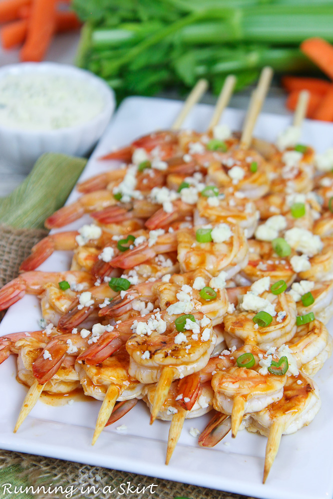 Shrimp on a white plate with celery and carrots.