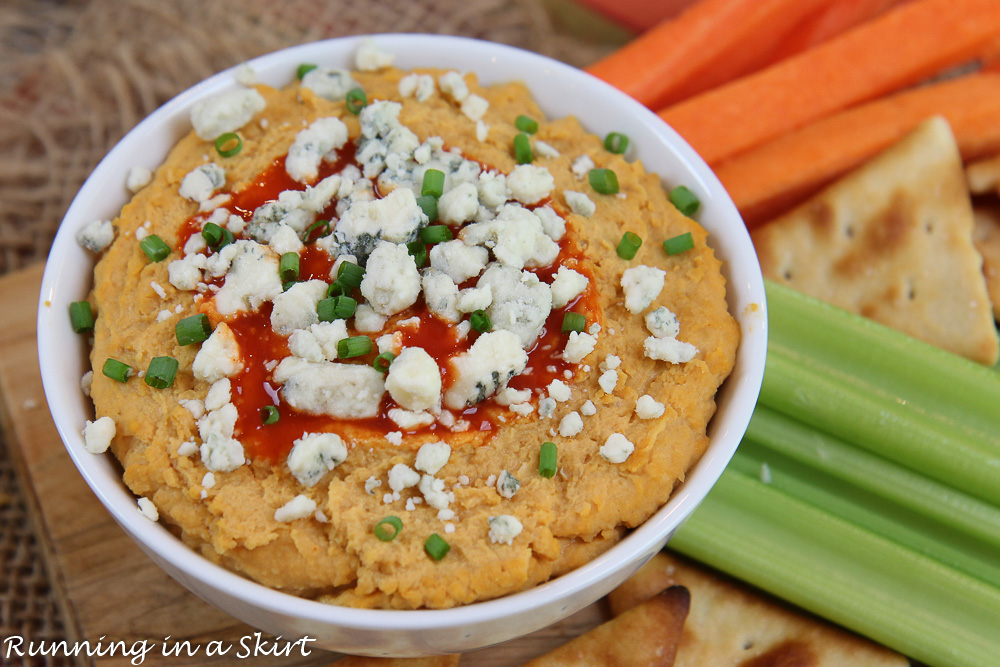 Buffalo Hummus in a white bowl topped with hot sauce and blue cheese.