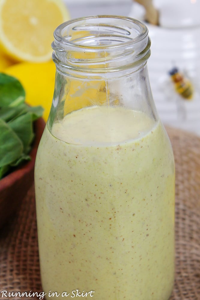Healthy Honey Mustard Dressing in a glass jar with lemons in the background.