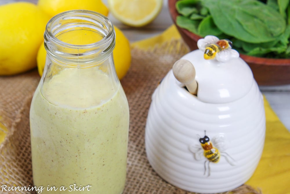 Healthy salad dressing in glass bottle next to honey pot.