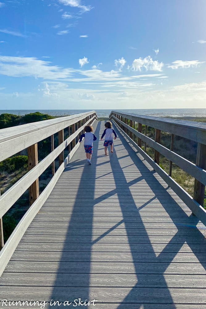 Toddlers running on beach boardwalk.