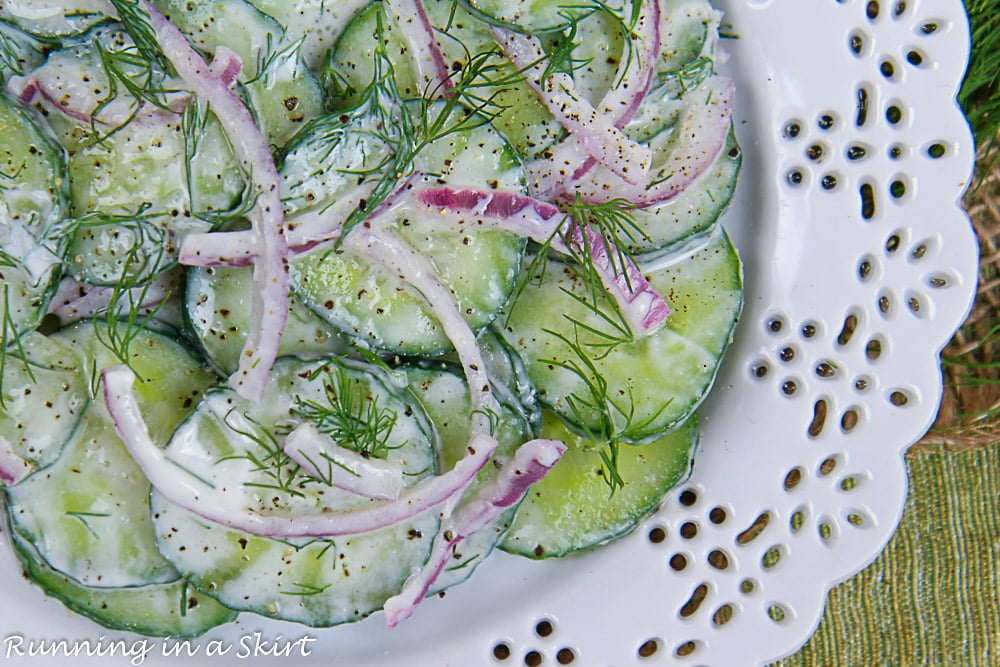 Closeup of the healthy cucumber salad on a white plate with dill and red onion.