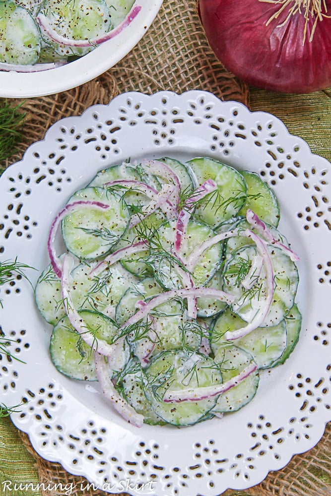 Overhead shot of Creamy Cucumber Dill Salad on a plate with a serving bowl.