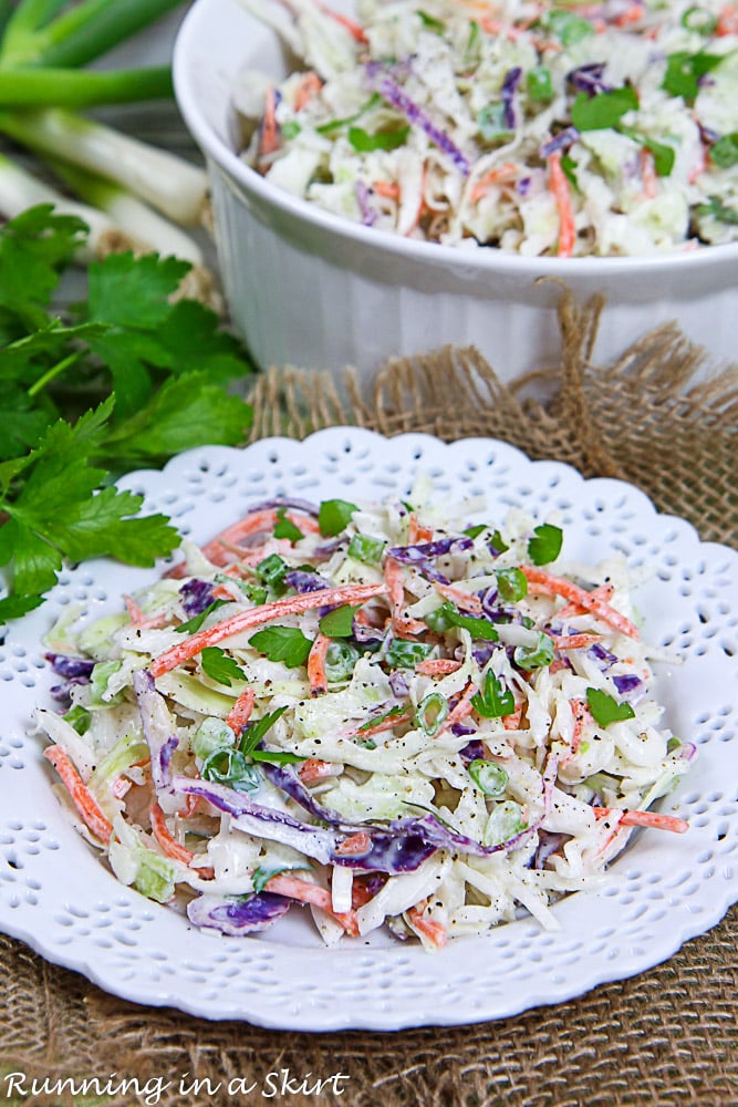 Healthy Coleslaw on a white plate with a serving bowl in the background.