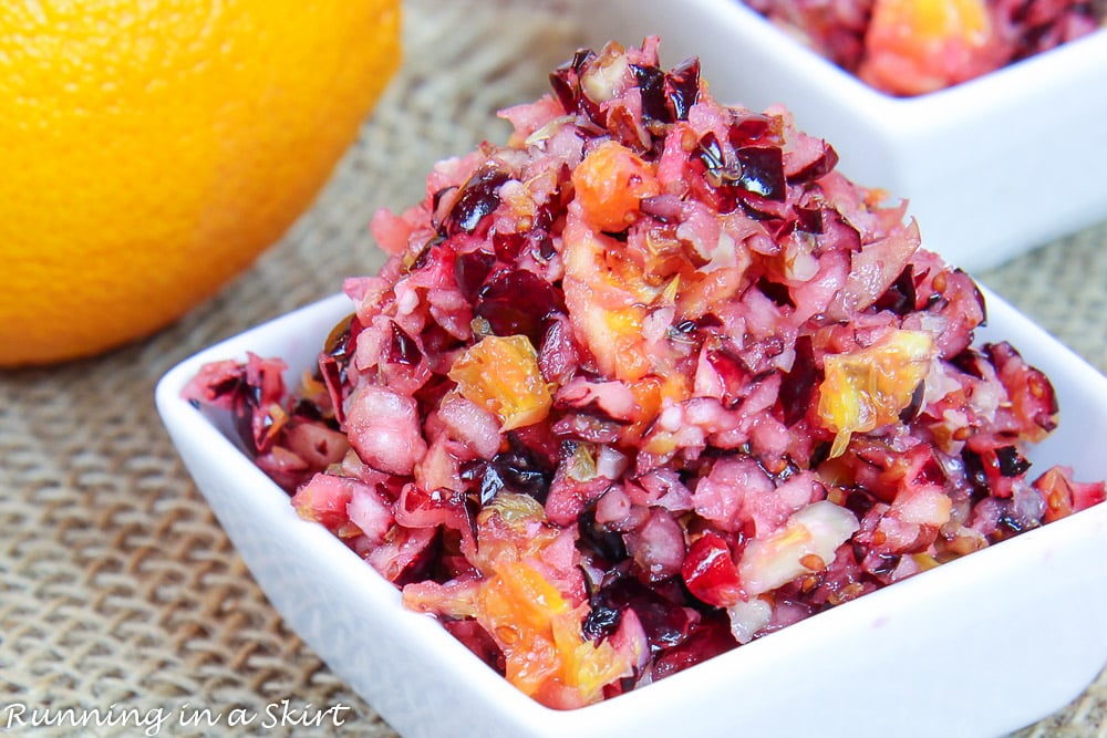 Small portion of Cranberry Orange Relish with an orange in the background.