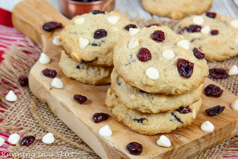 White Chocolate Cranberry Cookies on a cutting board stacked high up.