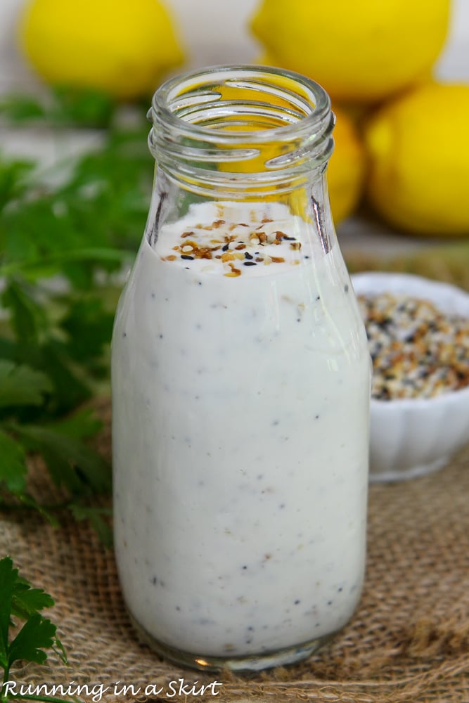 Everything Bagel Ranch Dressing in a glass bottle with lemons and parsley in the background.