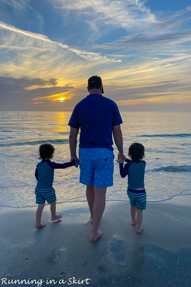 Dad holding sons hands at sunset.