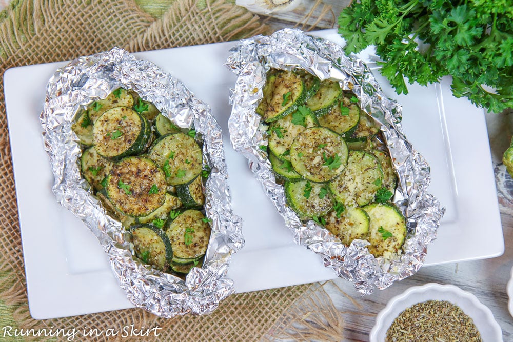 Two zucchini foil packets on a white plate.