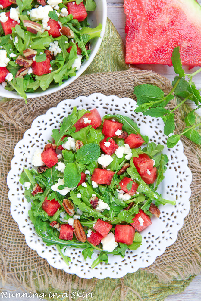 Watermelon Arugula Salad on a white plate with a slice of watermelon on the side.