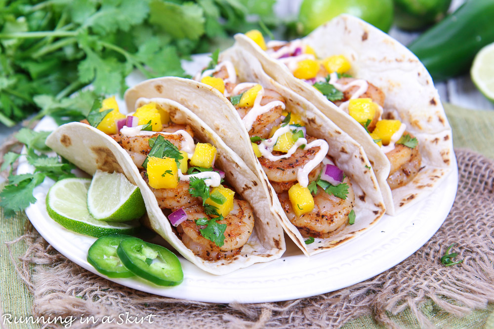 Blackened Shrimp Tacos with Mango Salsa on a white plate with lime wedges.