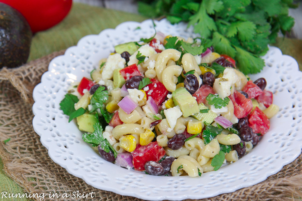 Mexican Macaroni Salad on a white plate with cilantro in the background.