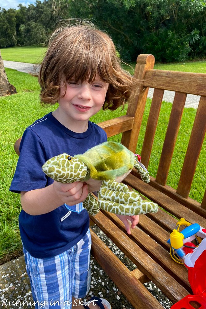 Boy holding stuffed turtle from gift shop.