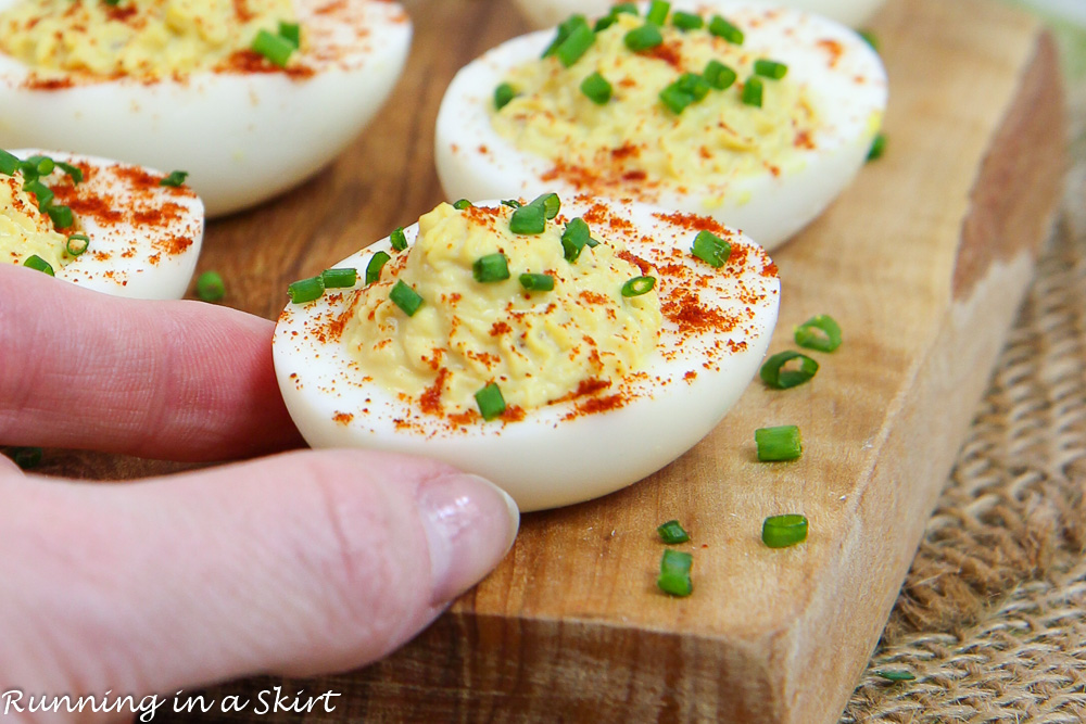 Close up of Greek Yogurt Deviled Eggs No Mayo with hand grabbing it.