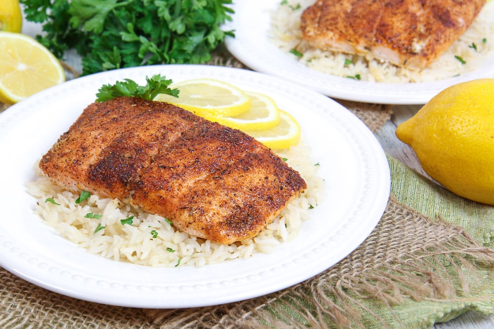 Baked Blackened Salmon recipe on a white plate with rice and lemon.
